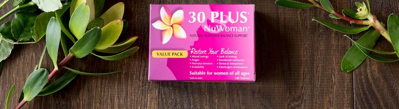 Box of 30 PLUS NuWoman on a table with flowers